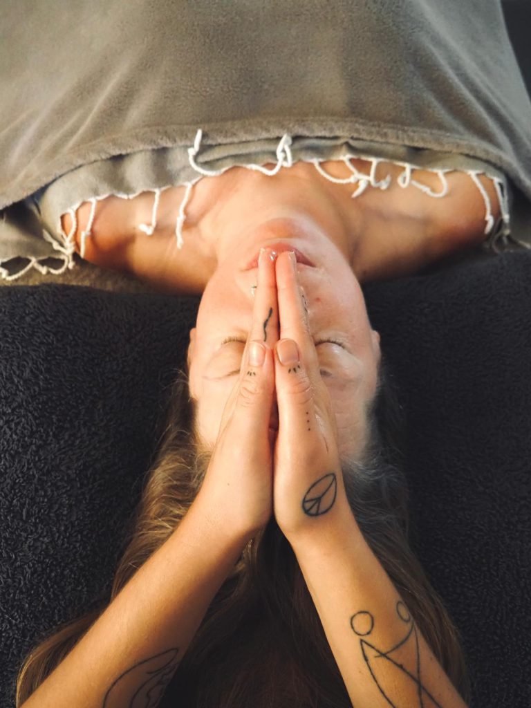 Hands resting gently above a client’s face during a Reiki session