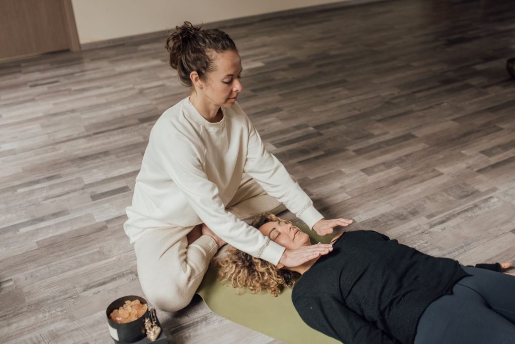 A practitioner working beside someone resting on the floor