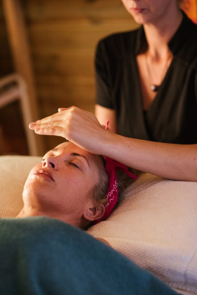 A Reiki practitioner with their hands resting lightly at the head